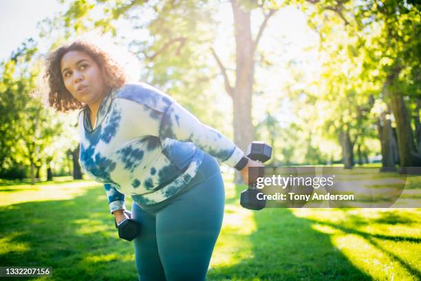 young woman working out with hand weights outdoors - blue leggings stock pictures, royalty-free photos & images