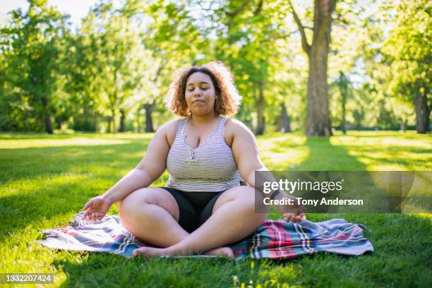 young woman meditating sitting on blanket in park - suburb park stock pictures, royalty-free photos & images