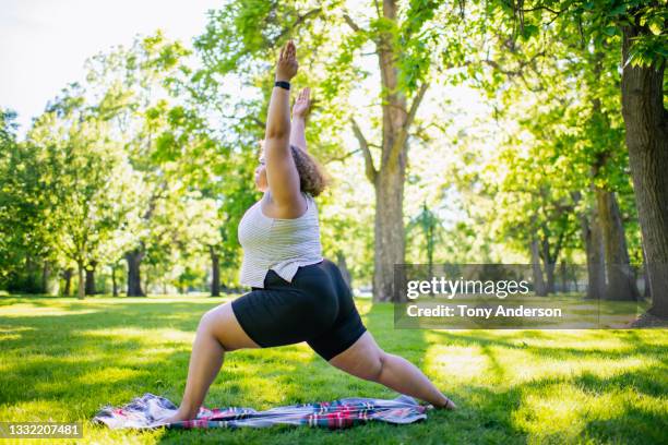 young woman practicing yoga outdoors in park - warrior position stock pictures, royalty-free photos & images