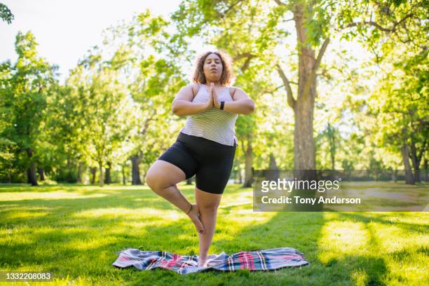 young woman practicing yoga outdoors in park - tree position stock pictures, royalty-free photos & images