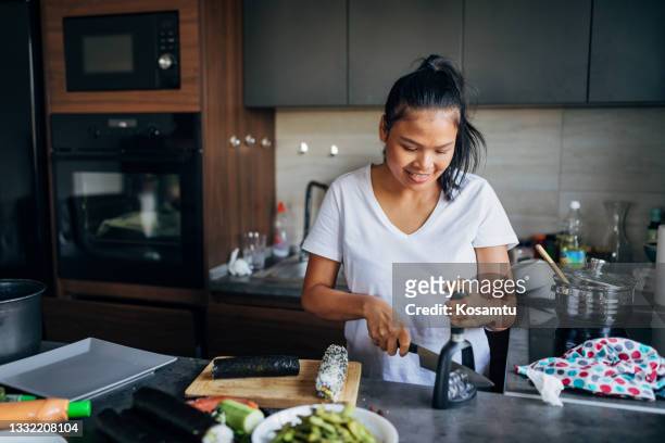 thai woman, sharpening her kitchen knife, so when she cut sushi rolls on the bite pieces, they can be same - woman sleep stockfoto's en -beelden