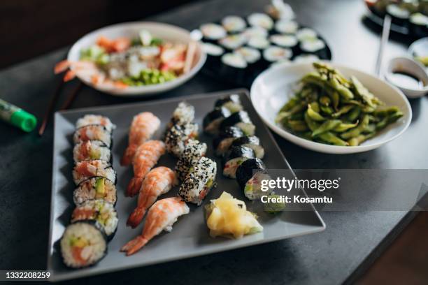 sushi plate with traditional, inside-out and nigiri sushi rolls and plate with side dish with edamame - shrimp edamame stock pictures, royalty-free photos & images