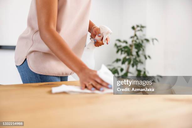 latin businesswoman cleaning the office desk with disinfectant - kitchen paper stockfoto's en -beelden