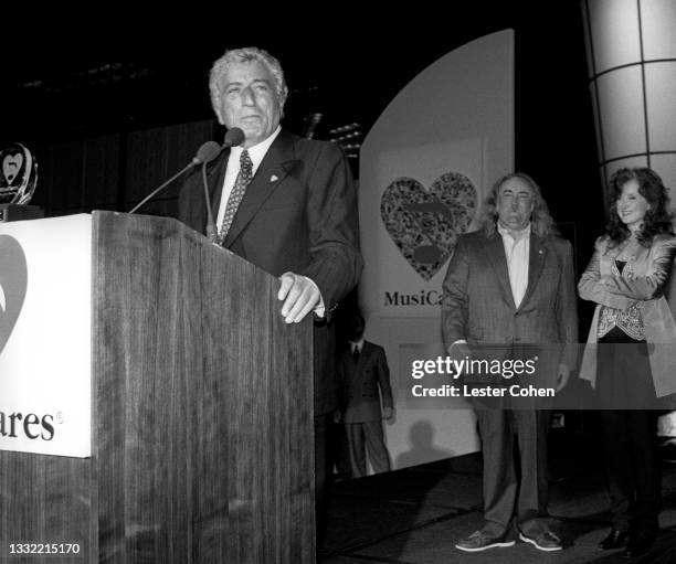 American singer of traditional pop standards, big band, show tunes, and jazz Tony Bennett speaks at the podium as American singer-songwriter and...