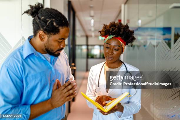 portrait of young female doctor of african-american ethnicity and her patient. - global healthcare stock pictures, royalty-free photos & images