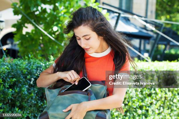 mujer joven sacando el teléfono de su bolso - bolso abierto fotografías e imágenes de stock
