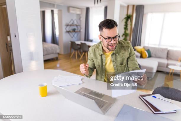 happy young man reading documents and celebrating. - financial freedom stock pictures, royalty-free photos & images