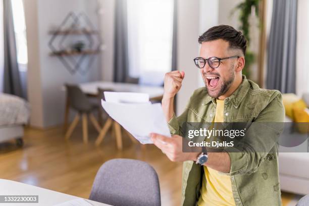 joven feliz sosteniendo papeleo y celebrando. - debt fotografías e imágenes de stock