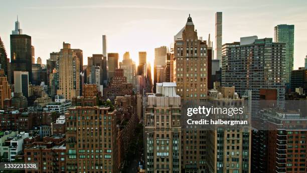 sun shining down new york streets at dusk from east river - aerial - roosevelt island stock pictures, royalty-free photos & images