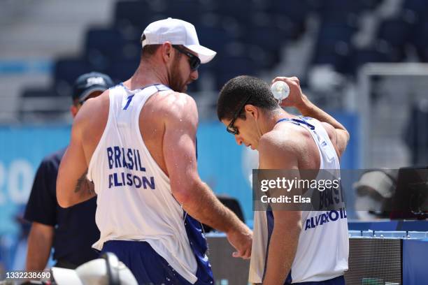 Alison Cerutti of Team Brazil and Alvaro Morais Filho cool down between plays against Team Latvia during the Men's Quarterfinal beach volleyball on...