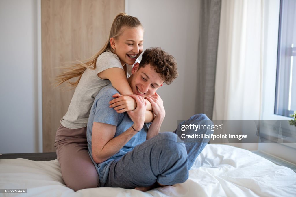 Portrait of young couple indoors at home, having fun on bed.