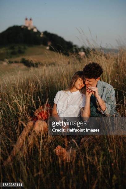portrait of young couple on a walk outdoors in nature, resting on blanket. - young couple enjoying a walk through grassland stock pictures, royalty-free photos & images