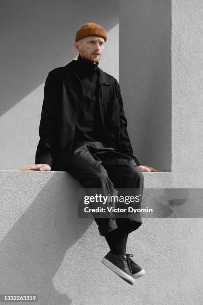 young redhead skinny man on the windowsill - fashion men stock-fotos und bilder