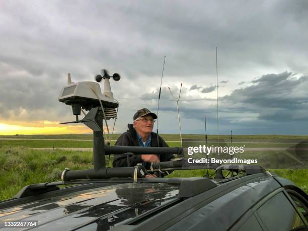 cazador de tormentas senior revisando el horizonte para una acción de tormenta severa después de ajustar la tecnología de la azotea en su vehículo - weather station fotografías e imágenes de stock