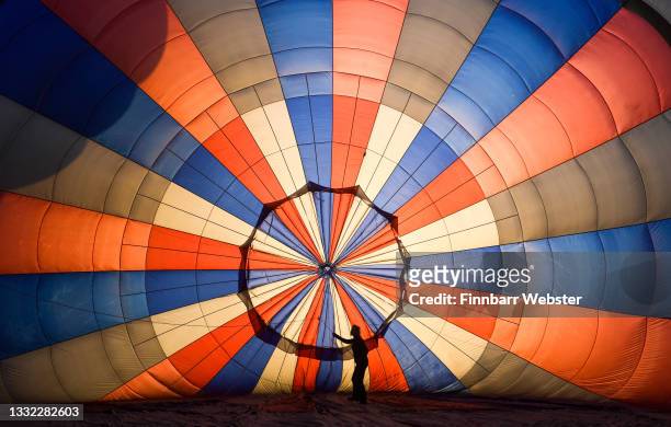 Person adjusts some lines inside a hot-air balloon before take off on August 04, 2021 in Bristol, England. "Fiesta Fortnight" takes place until...