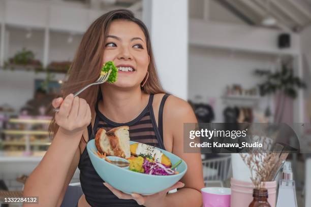 jeune femme chinoise mangeant une salade végétalienne saine dans un café - woman eating brocolli photos et images de collection