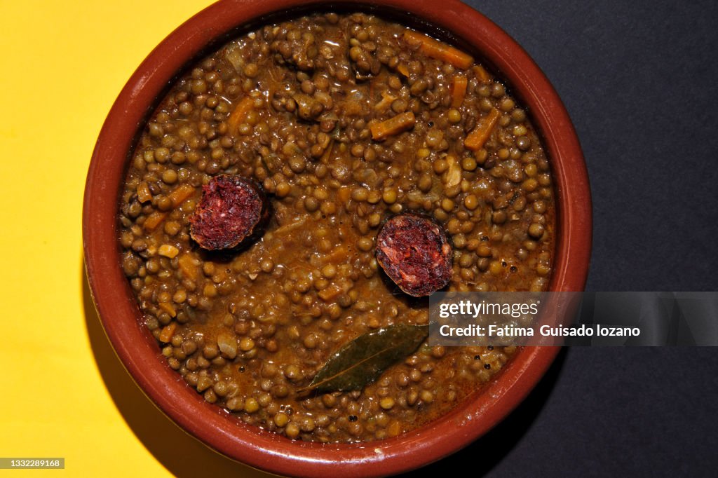 Close-up of lentils with chorizo on a yellow and brown background