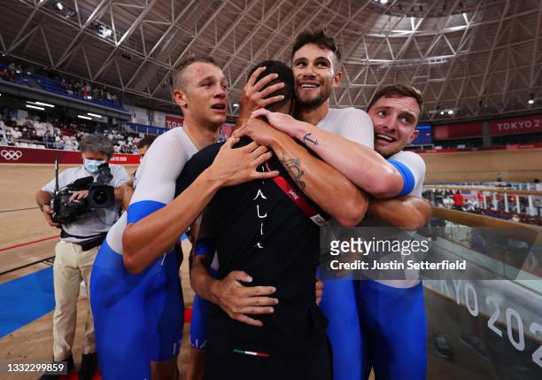 Jonathan Milan, Filippo Ganna and Simone Consonni of Team Italy are congratulated from they team coach after winning the gold medal and to set a new...