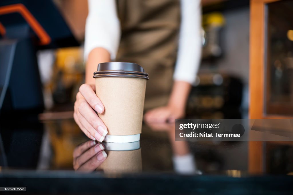 Please enjoy drinking a coffee. The unrecognizable waitress serving coffee to a customer in a cafe. Serving food and Drink, Point of Sale System.