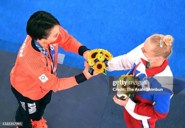 Bronze medalists Mai Murakami of Team Japan and Angelina Melnikova of Team ROC present their victory flowers each other on the podium at the medal...