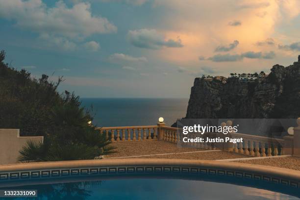 sunset view across villa's swimming pool on spanish mediterranean coastline - viewpoint stockfoto's en -beelden