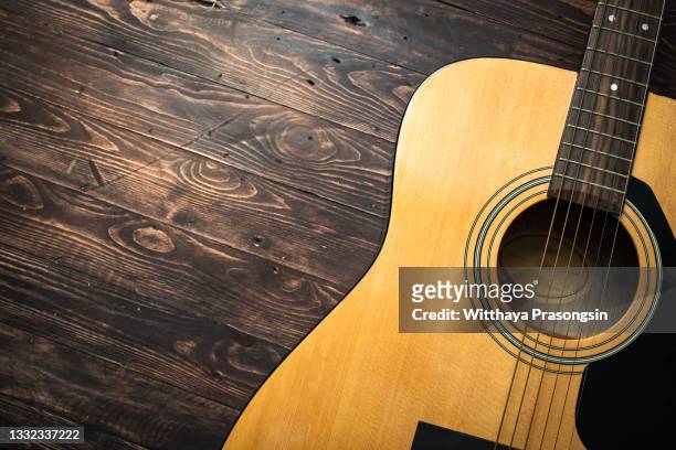 acoustic guitar resting against a wooden background with copy space - country and western music stock-fotos und bilder