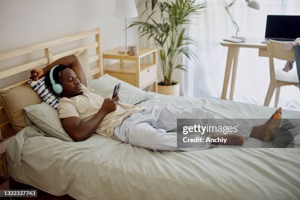 young man listening to music or podcast - bedroom radio stockfoto's en -beelden