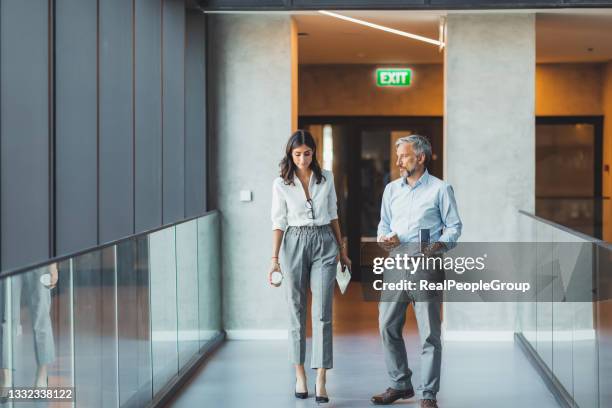equipo de colegas de camino a la oficina. hombre y mujer de negocios caminando, sosteniendo tabletas, taza de café y hablando. concepto de grupo empresarial - vestirse-formal fotografías e imágenes de stock