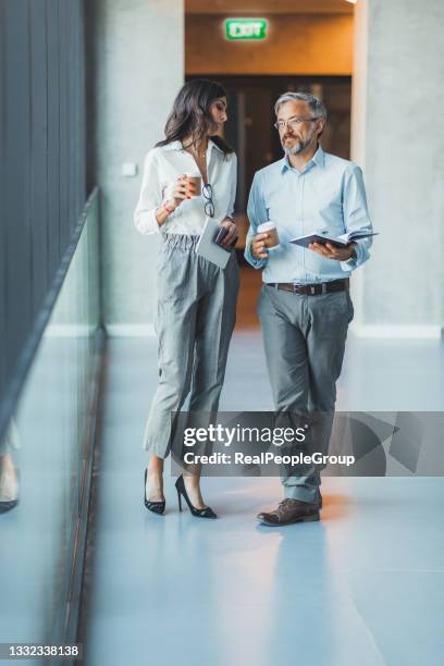 uomini d'affari sorridenti che camminano lungo la moderna sala o corridoio in ufficio, colleghi felici chat colleghi parlare andando a riunione o briefing in sala riunioni insieme, concetto di cooperazione - chief administration office foto e immagini stock