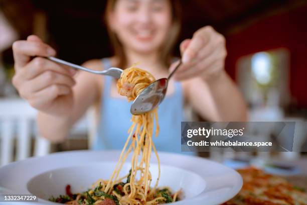 mujer alegre comiendo espaguetis picantes en el restaurante. - pasta fotografías e imágenes de stock