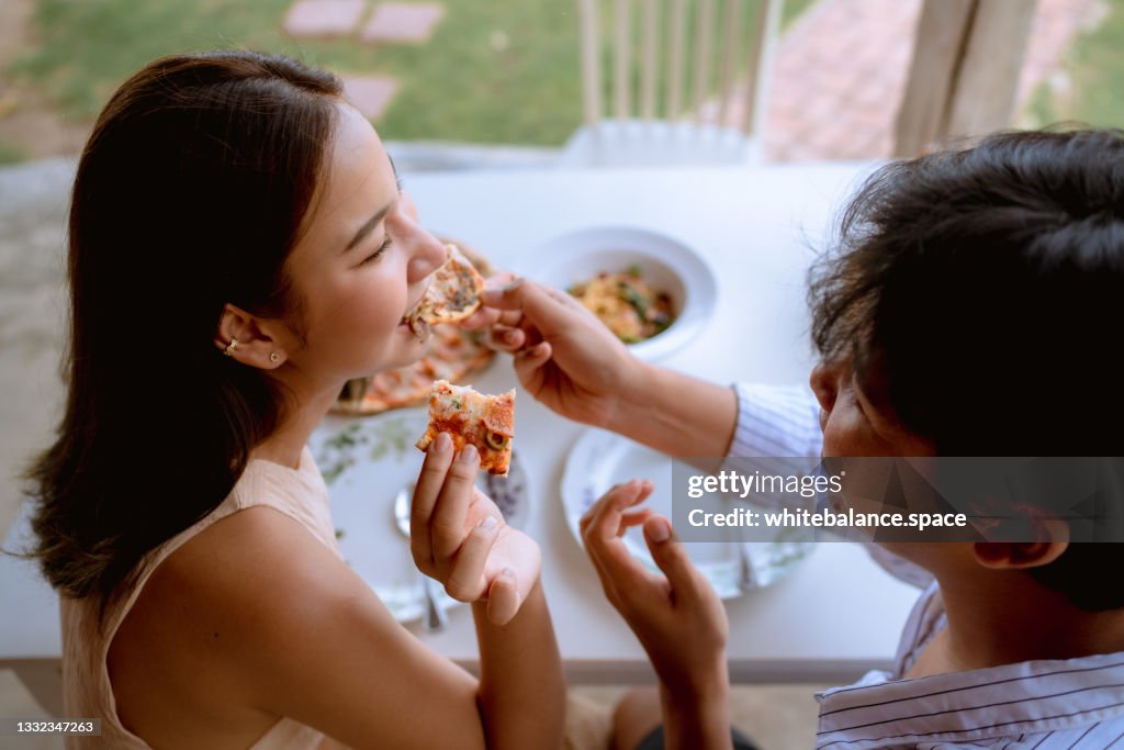 Cheerful couple enjoying with pizza at Italian cafe.