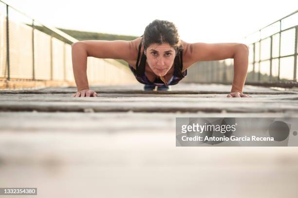 woman training push ups in bridge, copy space down - brustmuskulatur stock-fotos und bilder