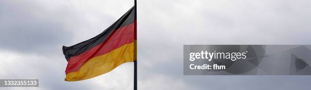 german flag with cloudy sky - german flag wallpaper stock-fotos und bilder
