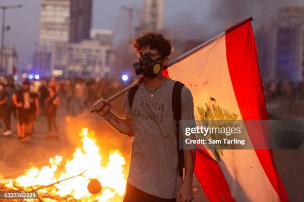 Protester holds a Lebanese flag during clashes with security forces after an anniversary commemoration of the Beirut port explosion, on August 4,...