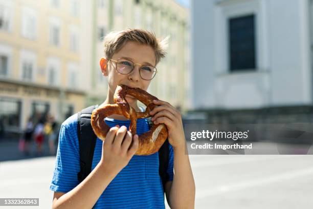 teenager beim brezeln in der straße von salzburg, österreich - brezel stock-fotos und bilder