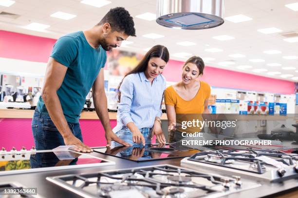 young couple receiving assistance from a saleswoman - mall home appliance stock pictures, royalty-free photos & images