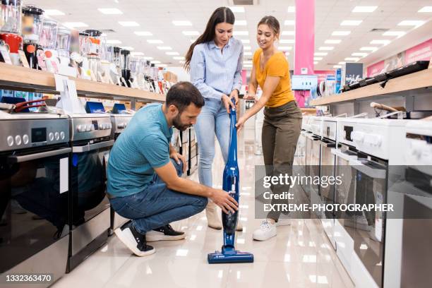 young couple gets assistance with the vacuum cleaner - stofzuiger stockfoto's en -beelden
