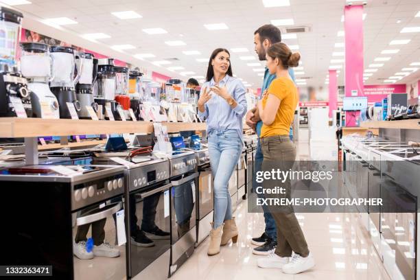 saleswoman helps customers with electric juicer - appliance store stockfoto's en -beelden