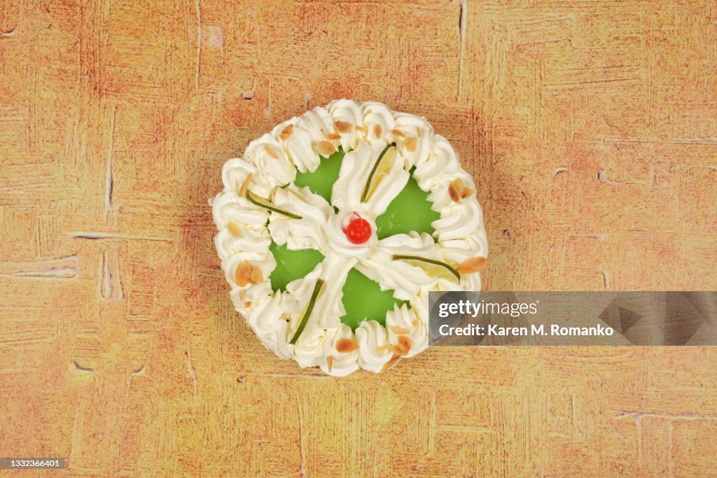 Key Lime Pie with a Cherry; Centered on Beige Background