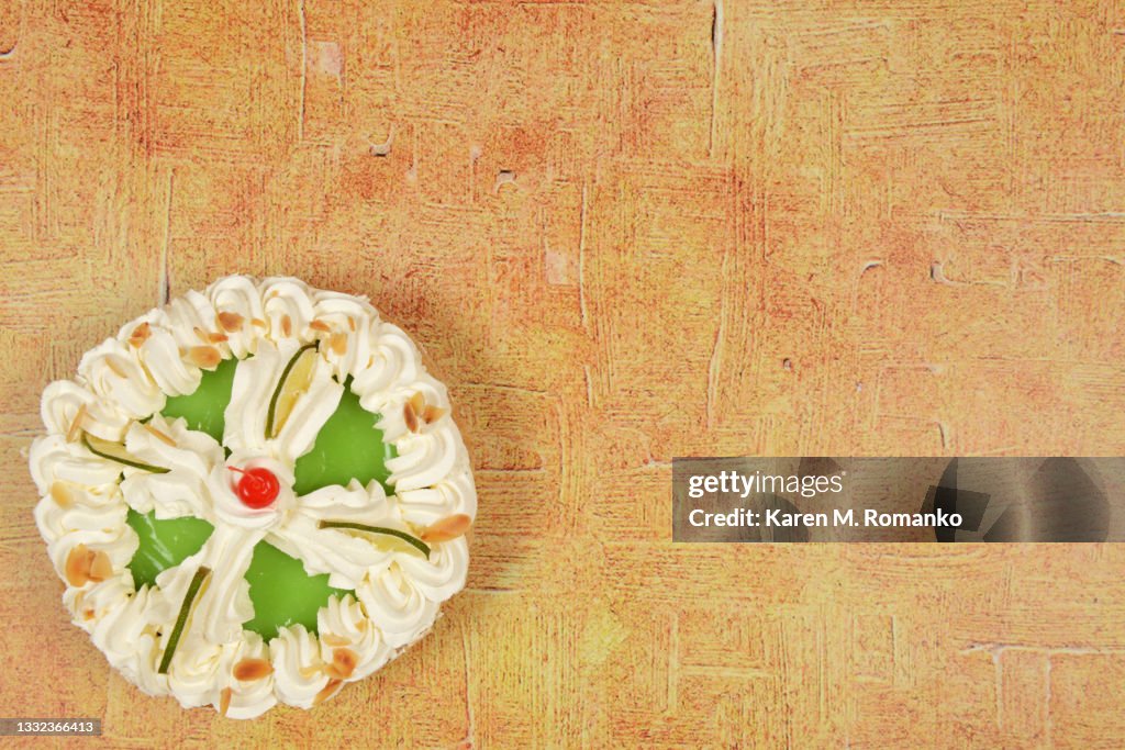 Key Lime Pie with a Cherry; Bottom Left on Beige Background