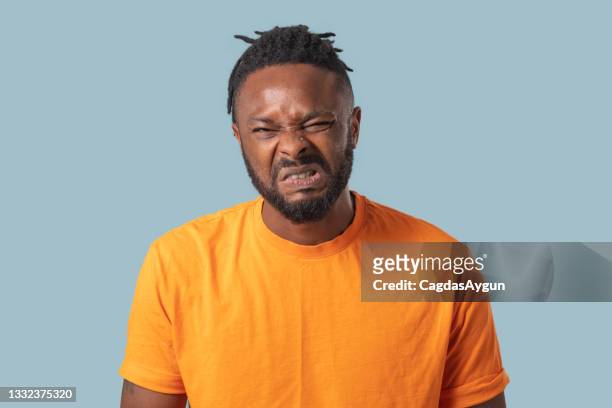 young man with a disgusting expression, human emotions, facial expression concept.
blue color background, studio shot . - offense stock pictures, royalty-free photos & images