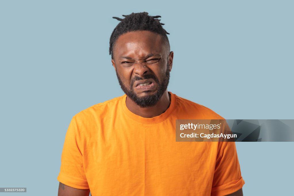 Young man with a disgusting expression, Human emotions, facial expression concept.
Blue color background, Studio shot .