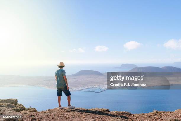 man on lanzarote cliff looking towards la graciosa island - lanzarote stock pictures, royalty-free photos & images