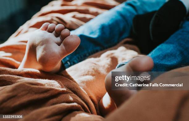 little bare feet on a soft bed, focus on soles and toes - füße hochlegen stock-fotos und bilder