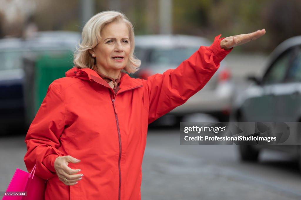 Retrato de uma idosa que está parada na Rua da Cidade e tentando pegar um passeio.