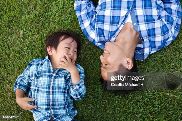 father and child who have lain down on the lawn - asian father son foto e immagini stock