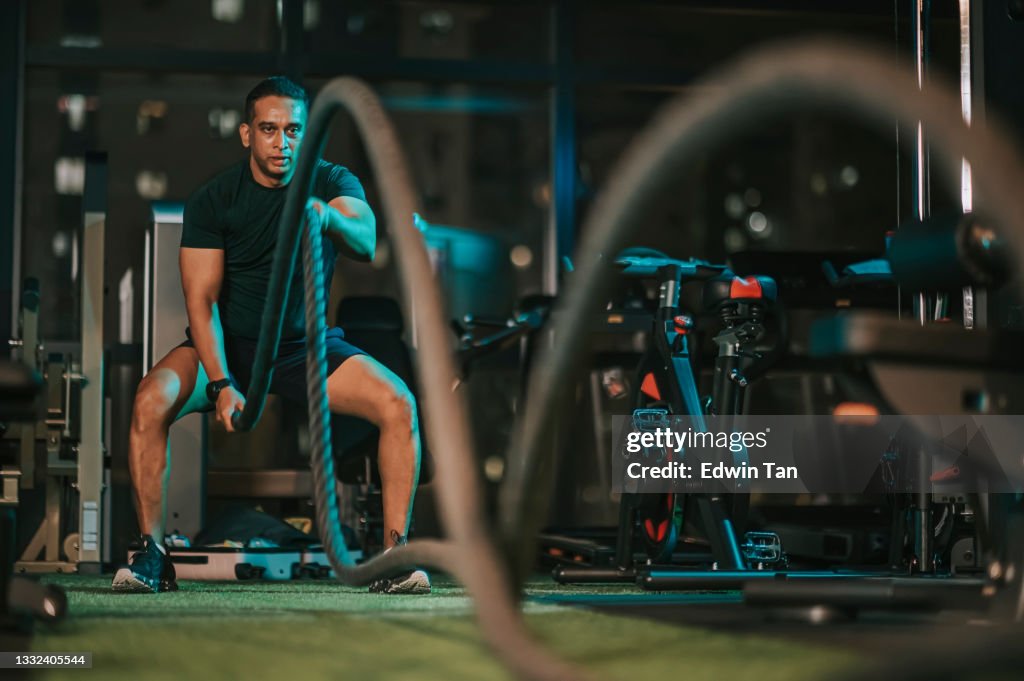 Asiatischer indischer Mid Adult Macho-Mann übt Kampfseil im Fitnessstudio