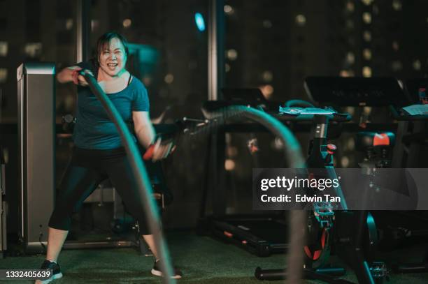 body positive asian chinese mid adult woman practicing battle rope in gym - battle rope stock pictures, royalty-free photos & images