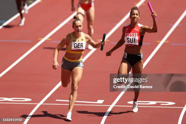 Gina Luckenkemper of Team Germany runs ahead of Salome Kora of Team Switzerland in round one of the Women's 4 x 100m Relay heats on day thirteen of...