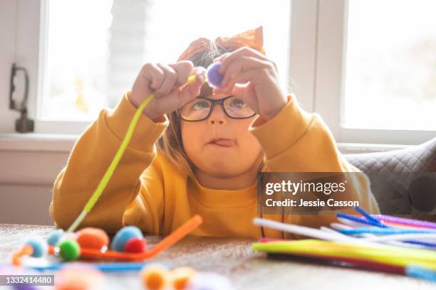 child with autism sitting at table doing craft - autismo foto e immagini stock